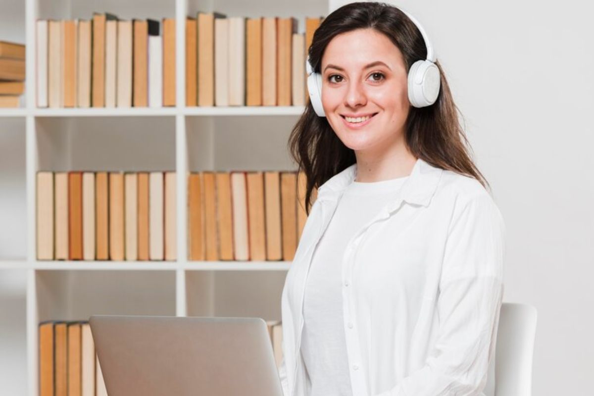 Uma secretária da escola dentro da sala sorri para a foto usando um headphone