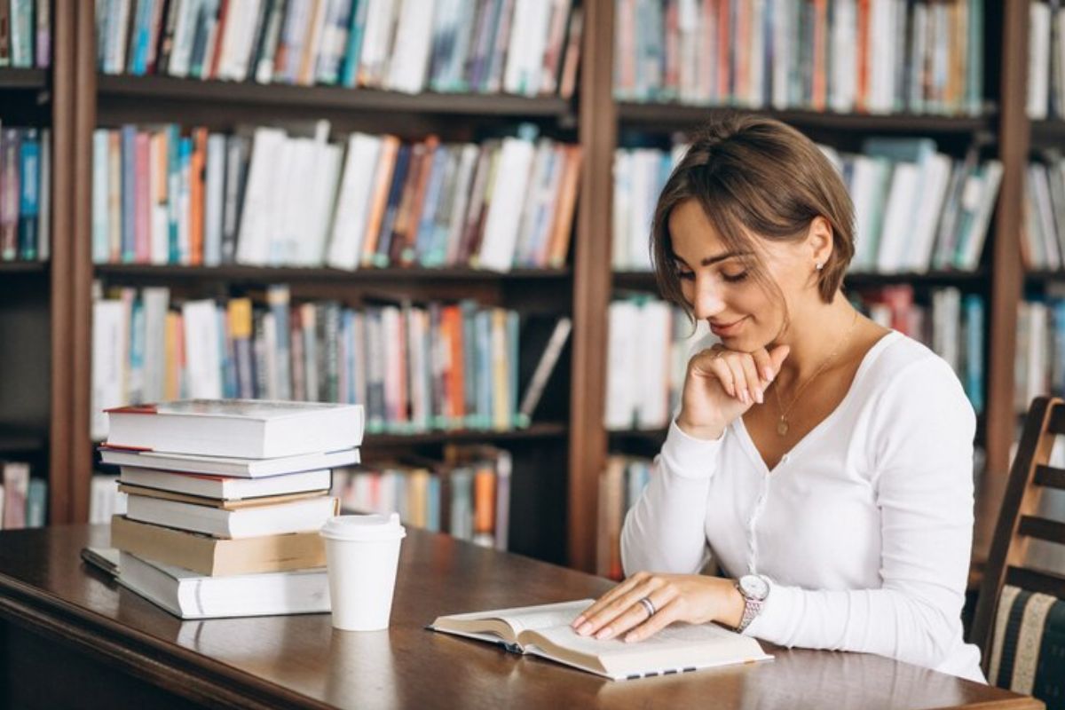 Uma jovem na biblioteca usa um livro para estudar após fazer a Matrícula Escolar Bahia 2025