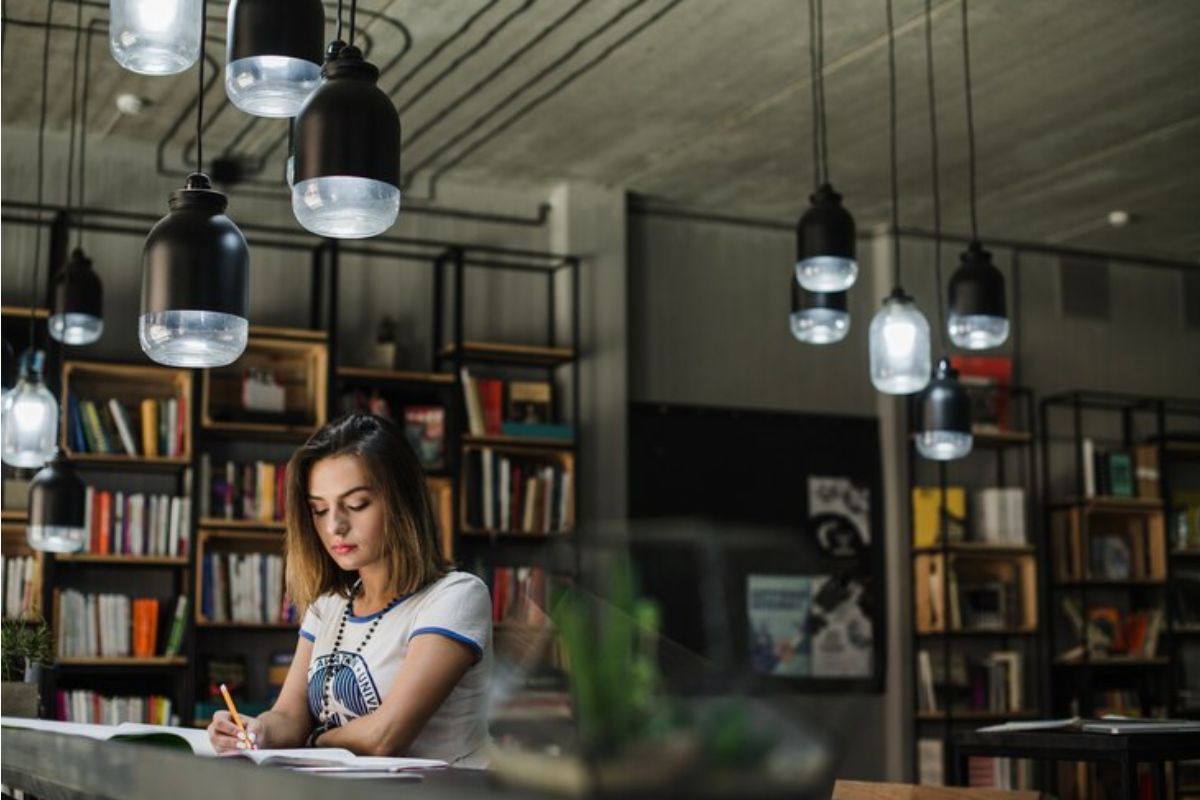 Uma estudante em frente ao seu notebook faz anotações no caderno sobre a Matrícula Online MA 2025