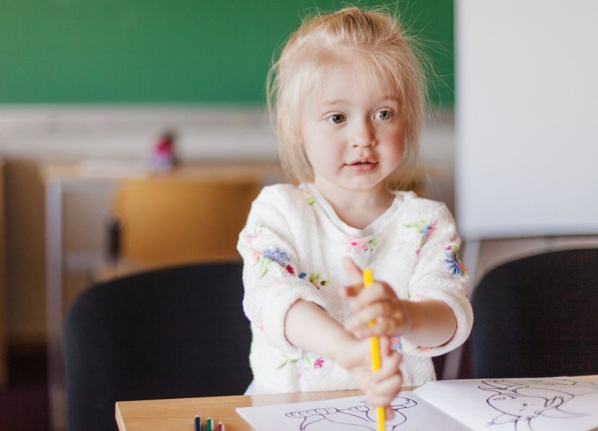 Criança desenha sentada em sua mesa na escola