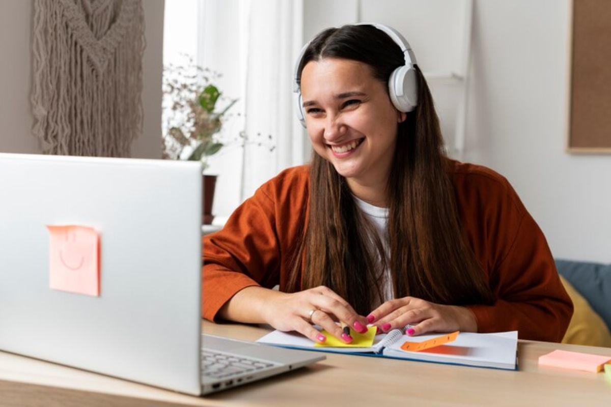 Uma estudante acessa o portal de Matrícula Escolar PR 2025 pelo seu notebook. Ela usa um headphone e sorri