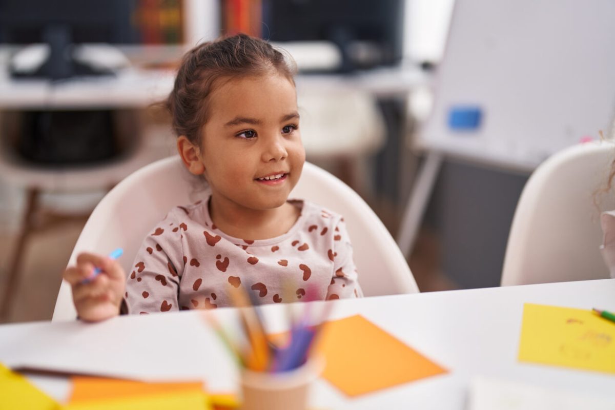 Bebê sentada na mesa da sala de aula da creche 