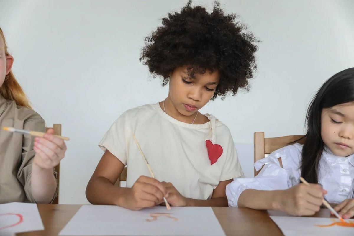 Três estudantes fazem desenho em uma folha. Elas estudam após o período de Matrícula Escolar Cabo Frio 2025