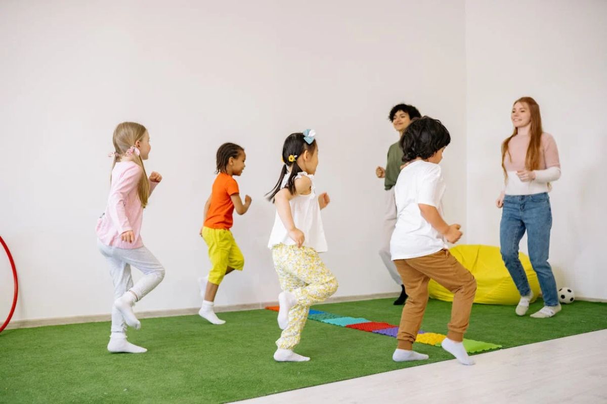 Um grupo de crianças brincando na escola. À frente estão duas professoras