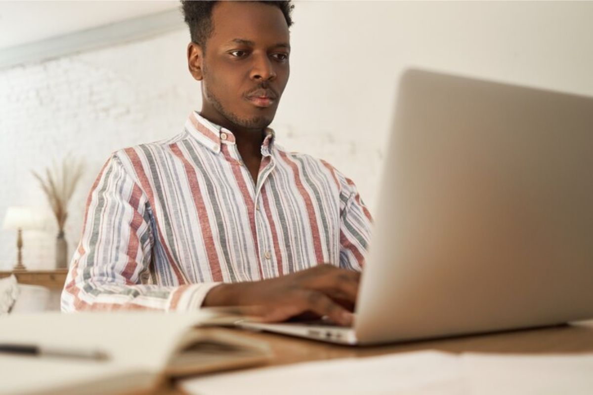 Um estudante em frente ao notebook dentro de seu quarto faz a matrícula segundo semestre UNEB 2025