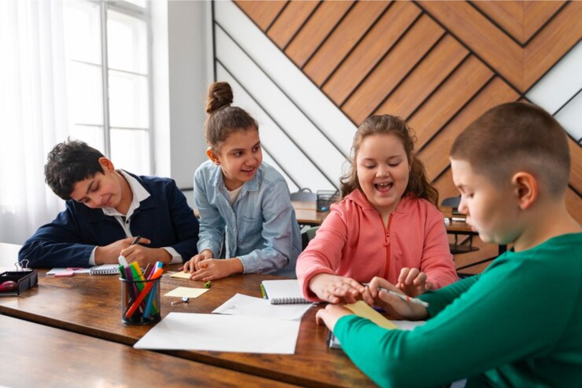 Um grupo de estudantes da educação infantil na sala de aula fazem um trabalho em grupo