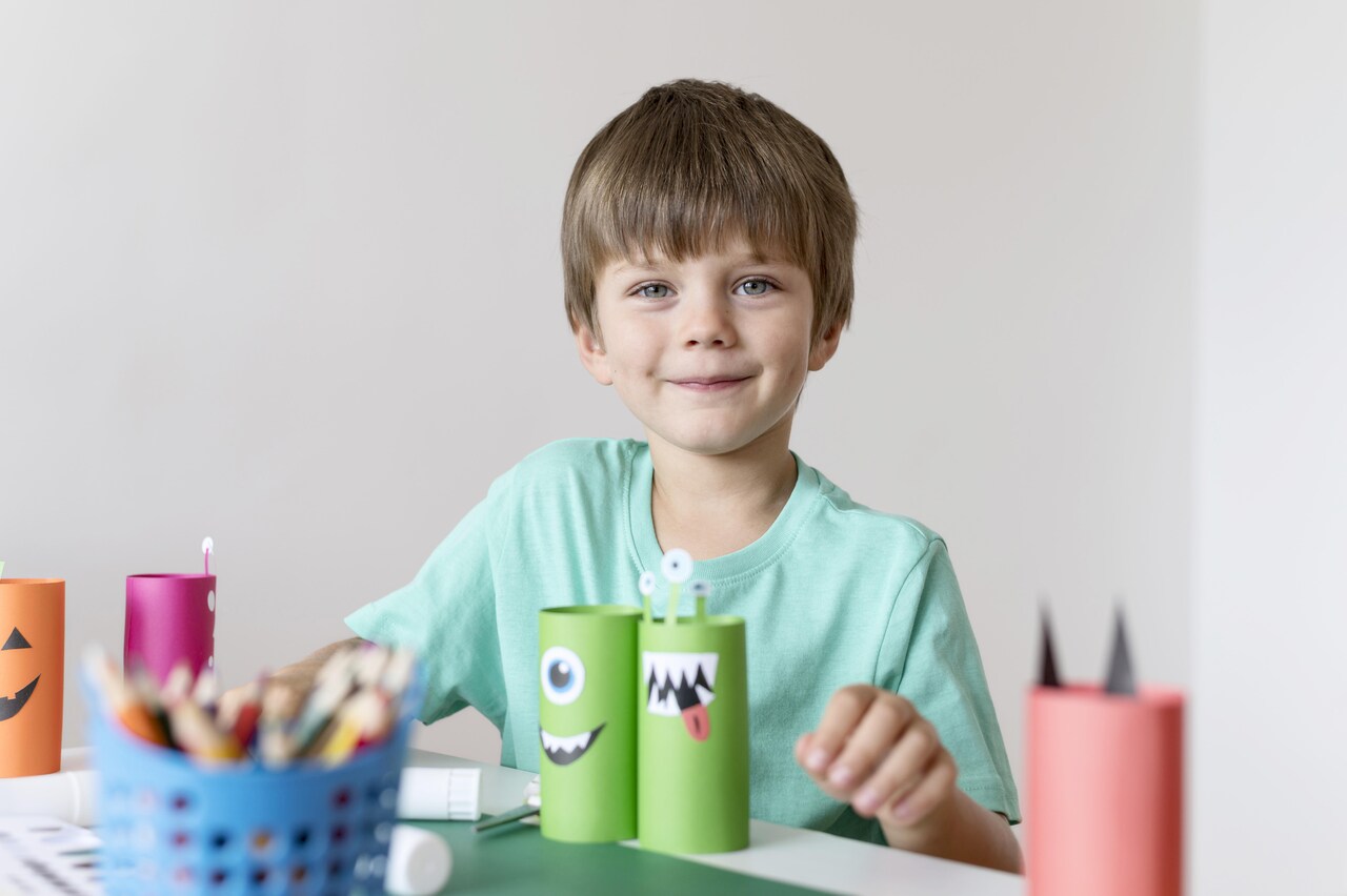 Menino posa sorridente durante atividade da pré-escola 