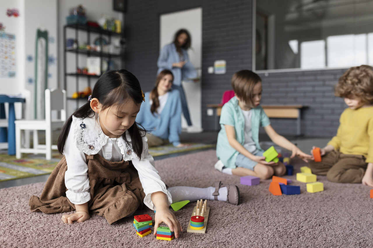 Crianças brincam sob supervisão de professora na pré-escola