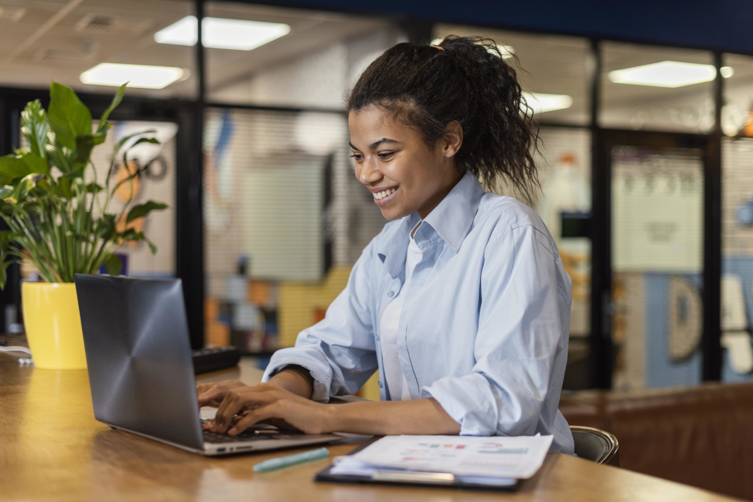 Mulher sorrindo enquanto digita em um notebook